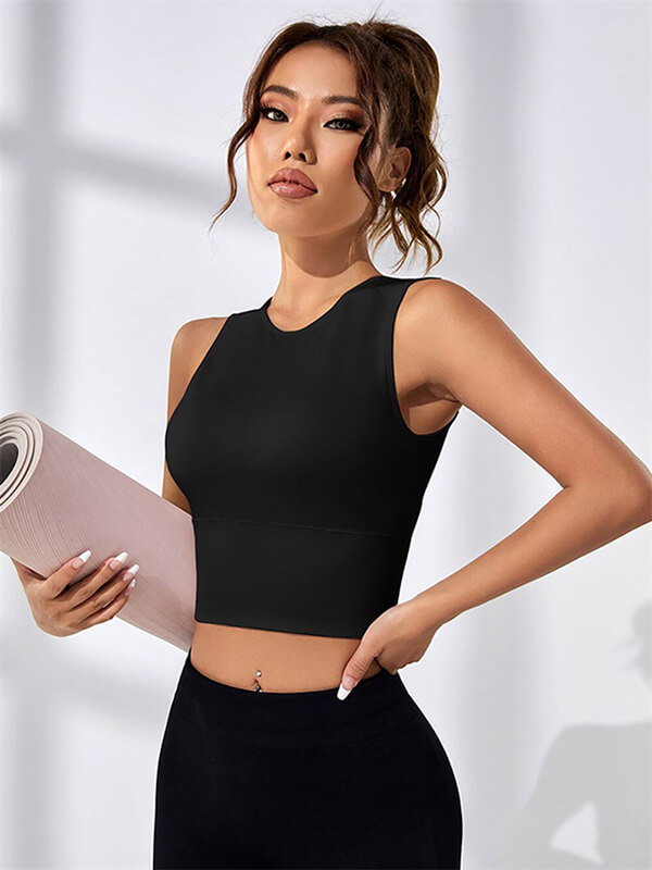 Woman wearing a black backless short tank top for Pilates, holding a yoga mat, perfect for workouts with quick-dry fabric.